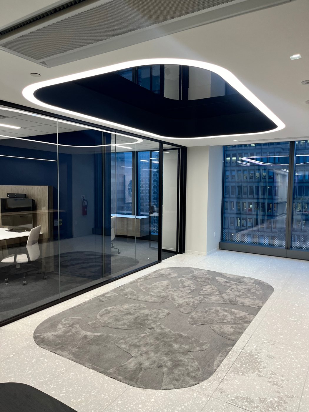 Large illuminated LED cove ring around a recessed ceiling feature in a modern office