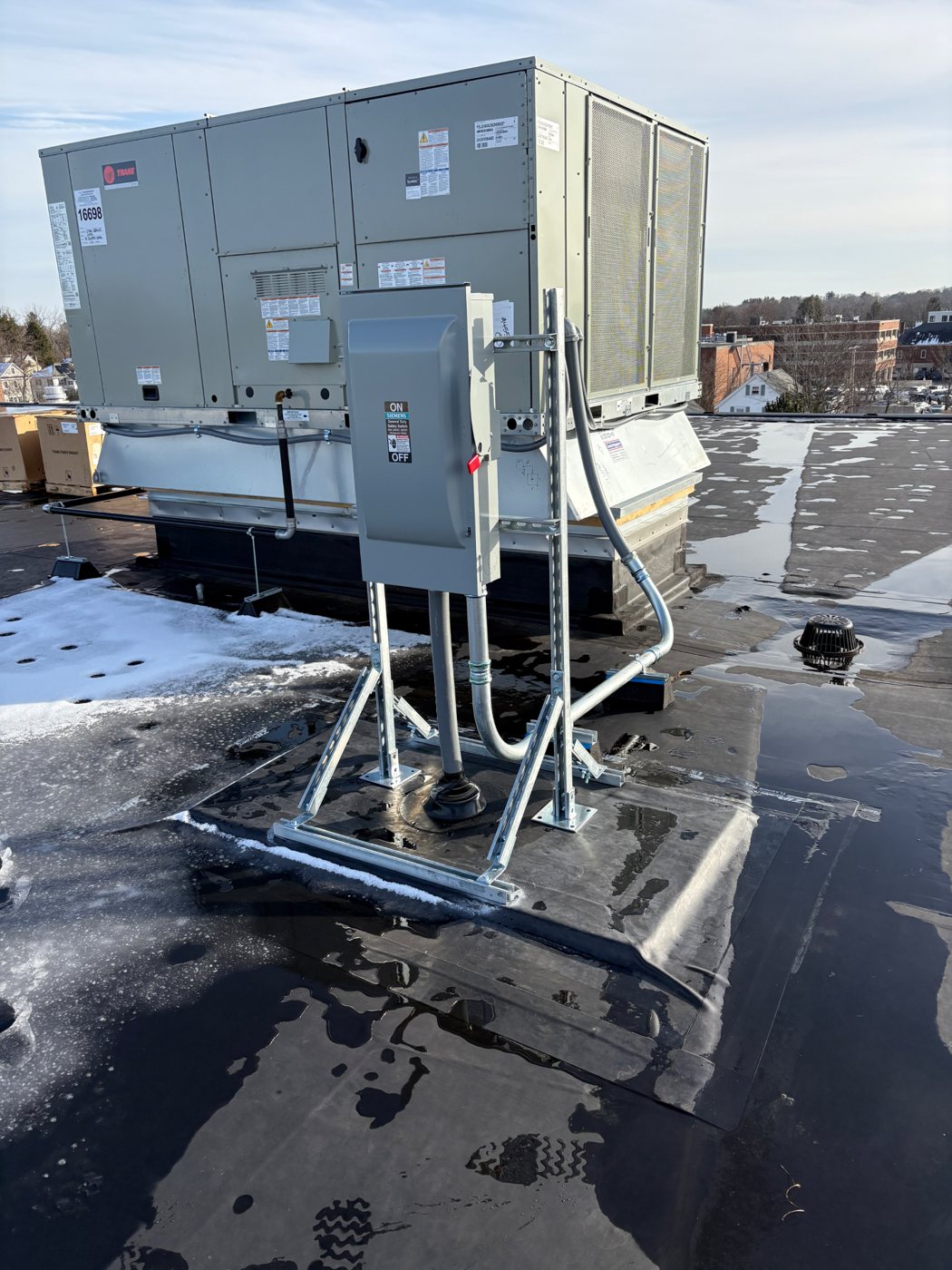 Rooftop disconnect on a galvanized stand with conduit feeding a commercial HVAC unit