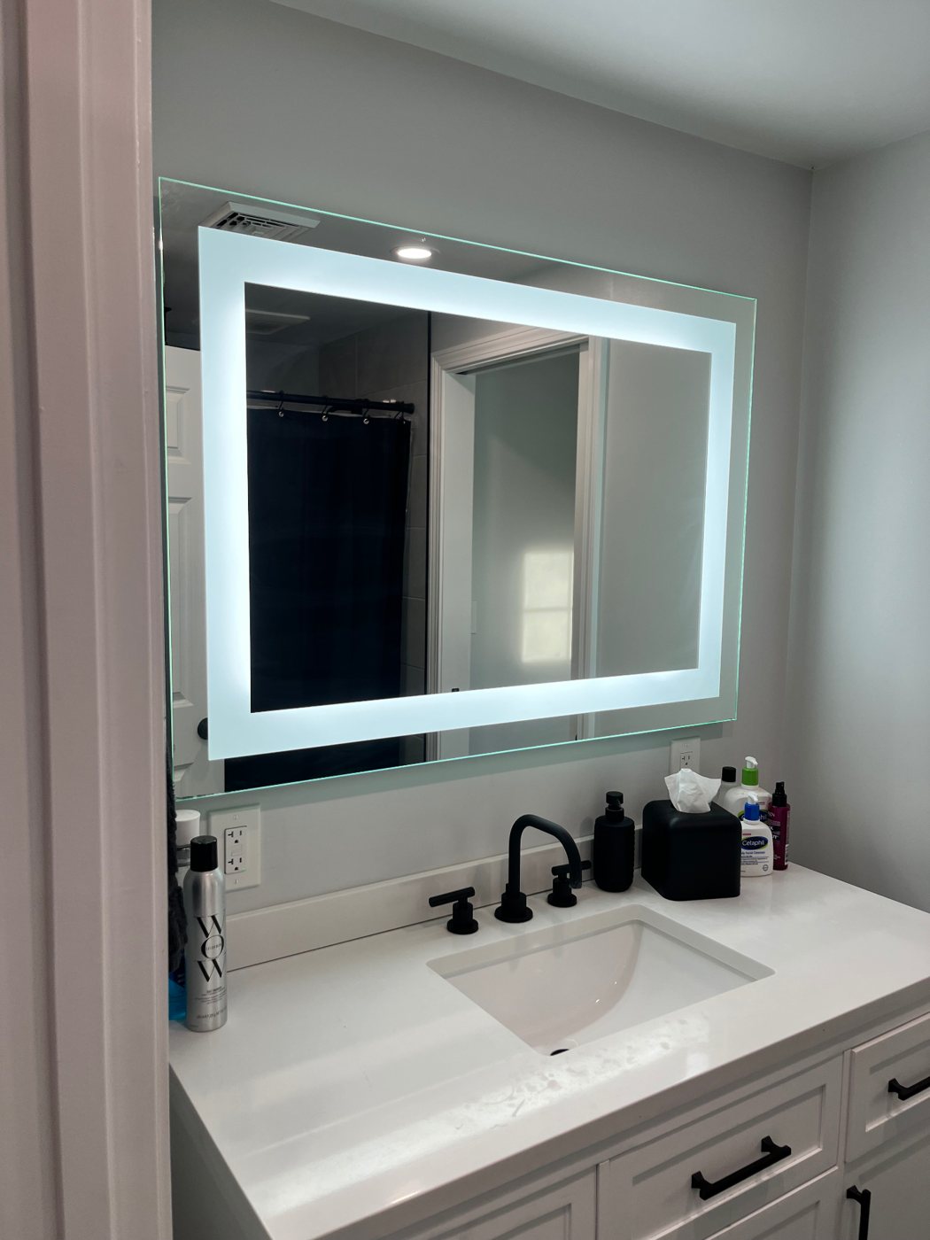 Backlit LED vanity mirror and GFCI outlet in a renovated bathroom